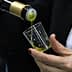 A person pouring olive oil from a bottle into a small glass cup during a tasting event. - Olive Oil Times