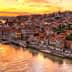 A panoramic view of Porto's riverfront at sunset with colorful buildings along the water's edge. - Olive Oil Times