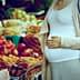 Pregnant woman standing in front of a fruit market display with various fruits. - Olive Oil Times