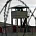 A prison watchtower surrounded by barbed wire fencing in a cloudy environment. - Olive Oil Times
