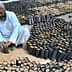 Two men preparing seedling pots filled with soil in a garden setting. - Olive Oil Times