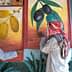 Two men in traditional attire examining wall murals depicting olives and dates. - Olive Oil Times