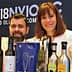 Two individuals giving thumbs up while posing with various olive oil bottles and awards. - Olive Oil Times