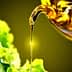 Olive oil being poured from a bottle onto fresh lettuce and cucumber slices. - Olive Oil Times
