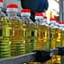 Row of plastic bottles filled with cooking oil on a production line in a factory setting. - Olive Oil Times