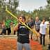 Group of people observing an olive harvesting demonstration with a worker using a pole. - Olive Oil Times