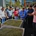 A group of people gathered around two large containers filled with olives during an olive oil production demonstration. - Olive Oil Times