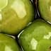Close-up of green olives submerged in brine with a glossy surface. - Olive Oil Times