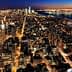 Aerial view of New York City skyline illuminated at night with city lights and buildings visible. - Olive Oil Times