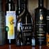 Various bottles of olive oil displayed on a shelf, featuring different brands and designs. - Olive Oil Times