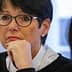 Woman with short black hair and glasses sitting at a table during a meeting, looking thoughtful. - Olive Oil Times