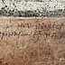 Faded ancient inscription carved into a stone wall with visible texture and cracks. - Olive Oil Times