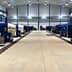 Row of industrial olive oil processing machines in a large facility with blue and gray colors. - Olive Oil Times