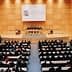 Interior view of a large conference hall during a World Trade Organization meeting with attendees seated. - Olive Oil Times