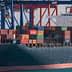 Container ship named Genoa loaded with colorful shipping containers at a port. - Olive Oil Times