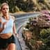 A woman jogging on a winding road with greenery and flowers along the side. - Olive Oil Times