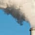 Two industrial smoke stacks releasing white vapor into a clear blue sky. - Olive Oil Times