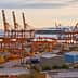 Container port in Piraeus, Athens with cranes and shipping containers along the waterfront. - Olive Oil Times