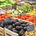 Assorted fresh vegetables displayed in wooden crates at a market stall, including tomatoes, cucumbers, and eggplants. - Olive Oil Times