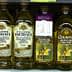Various bottles of olive oil displayed on a supermarket shelf, including Filippo Berio and Colavita brands. - Olive Oil Times