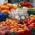 Assorted fresh fruits and vegetables displayed in crates at a market stall. - Olive Oil Times