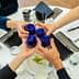 Four individuals toasting with blue glasses at a round table during a meeting. - Olive Oil Times