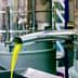 Metal olive oil extraction equipment with oil flowing from a spout into a container. - Olive Oil Times