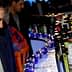 Man in a dark suit looking at a row of various bottles on a bar at an event. - Olive Oil Times