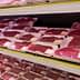 Various packages of red meat displayed on shelves in a supermarket meat section. - Olive Oil Times