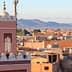 View of Marrakech cityscape featuring a prominent minaret and surrounding buildings under a clear sky. - Olive Oil Times