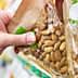 A hand reaching for a transparent package of almonds on a store shelf. - Olive Oil Times