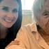 A woman with long dark hair smiling next to an elderly lady with gray hair wearing a light pink blouse. - Olive Oil Times