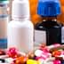 Various pharmaceutical bottles and colorful capsules arranged on a surface. - Olive Oil Times