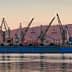 Cargo ship docked at the port of Volos with cranes and a tugboat nearby. - Olive Oil Times