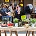 A table featuring various bottles of olive oil and fresh produce at an event. - Olive Oil Times