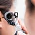 Healthcare professional examining a patient's ear with an otoscope in a clinical setting. - Olive Oil Times