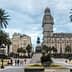 Statue of a horseman located in Plaza Independencia, surrounded by palm trees and buildings in Montevideo. - Olive Oil Times