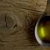 Metal spoon filled with olive oil resting on a textured wooden surface. - Olive Oil Times