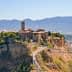 Aerial view of Civita di Bagnoregio, an ancient hilltop village in Italy, surrounded by mountains and valleys. - Olive Oil Times