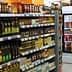 A grocery store aisle displaying various bottles of condiments and cooking oils on shelves. - Olive Oil Times
