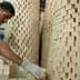 A man wearing gloves stacking rectangular soap blocks in a workshop environment. - Olive Oil Times