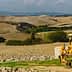 Yellow tractor parked near a barn in a rural agricultural landscape with rolling hills. - Olive Oil Times