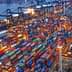 Aerial view of a shipping port filled with colorful containers and cranes at night. - Olive Oil Times