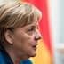 Profile view of Angela Merkel with short hair and a blue jacket, set against a blurred background. - Olive Oil Times