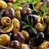 A bowl of assorted green and black olives with herbs and spices. - Olive Oil Times