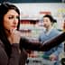Woman with long dark hair contemplating products in a grocery store aisle while a man is in the background. - Olive Oil Times