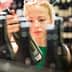 Woman examining a wine bottle while shopping in a store with multiple bottles in the background. - Olive Oil Times