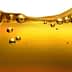 Close-up image of olive oil with bubbles suspended in the liquid. - Olive Oil Times