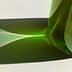 Green glass bottle casting a light reflection on a white surface. - Olive Oil Times