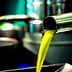 Stream of bright green olive oil pouring from a metal tap into a container. - Olive Oil Times